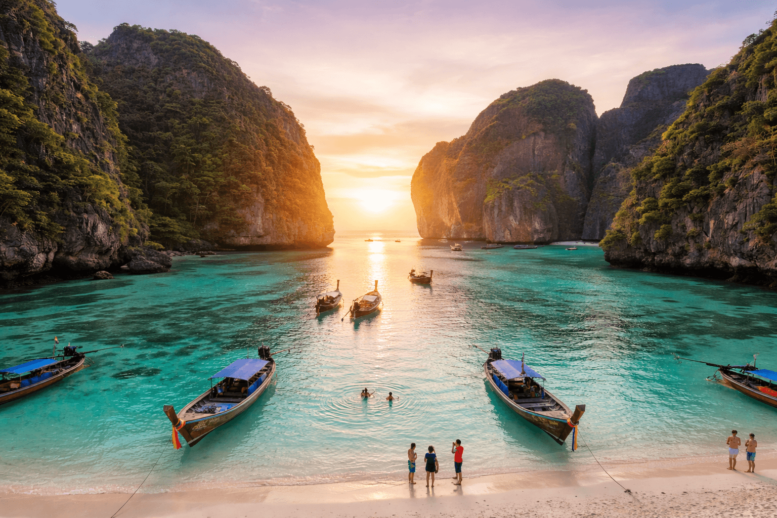 Long-tail boats anchored in turquoise waters between limestone cliffs at Phi Phi Islands, Thailand during sunset