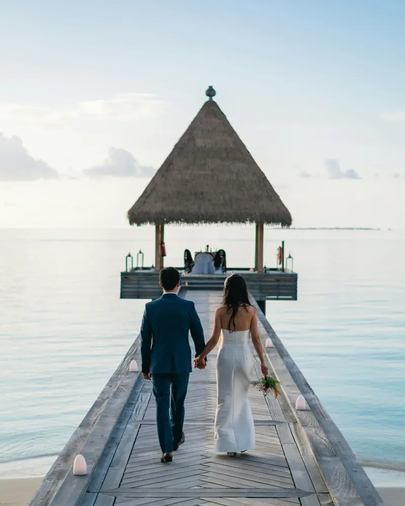 Couple walking to an overwater villa in the Maldives Couple walking to an overwater villa in the Maldives – honeymoon packages from Kerala by Tourfly